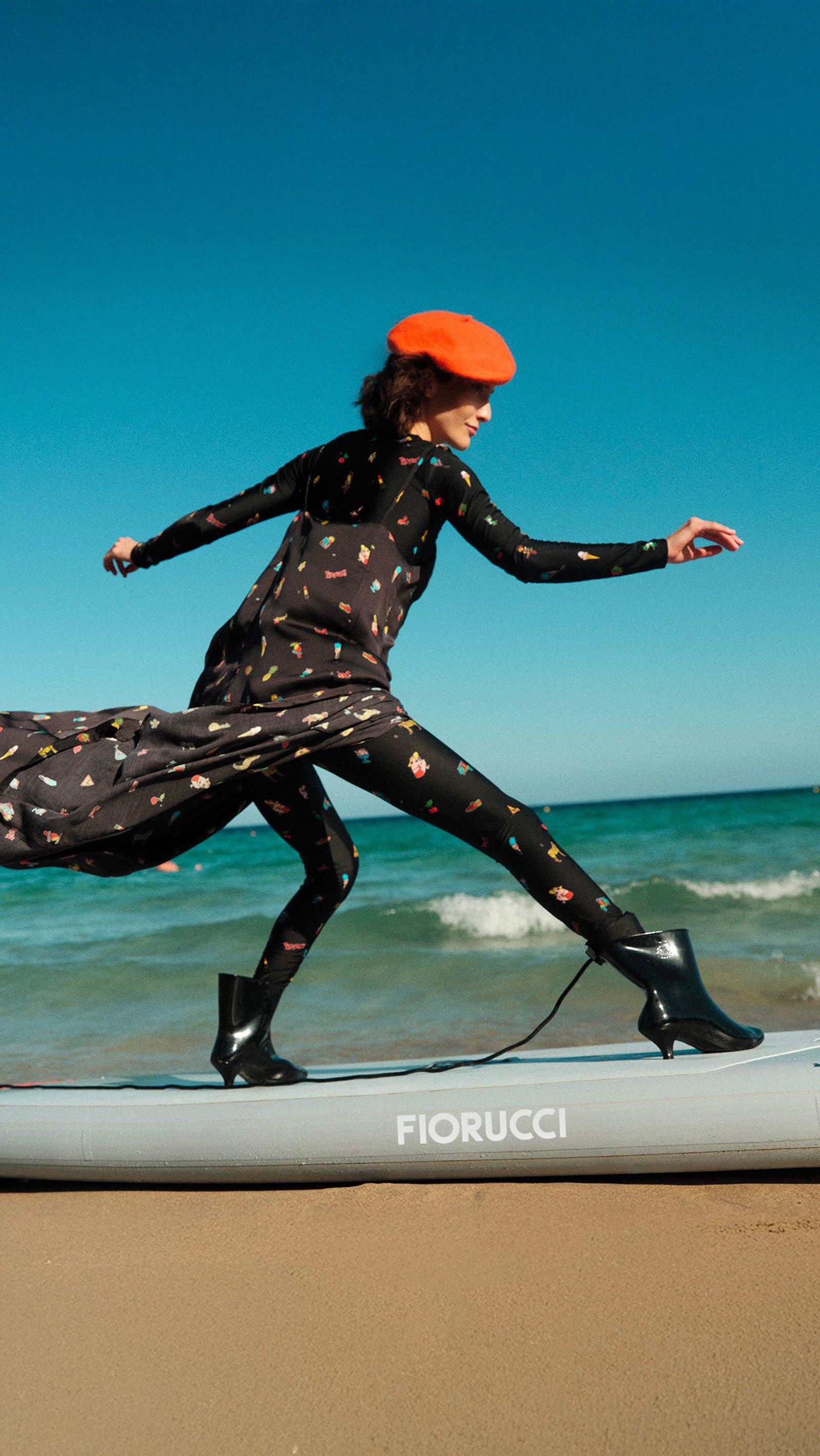 The model is wearing the Toys Print Slip Maxi Dress in Black, Toys Print Leggings in Black, Toys Print Long Sleeve Crop Top in Black, Love Boots in Yellow.